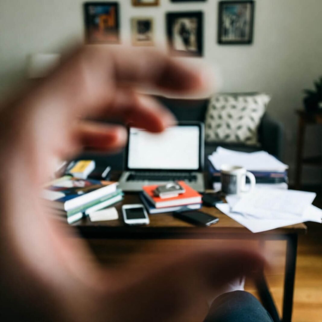 Blurry thumb over chaotic coffee table mess.
